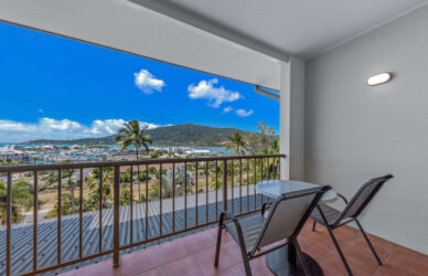 Balcony view with ocean and mountain scenery, featuring two chairs and a table for relaxation at the resort hotel.