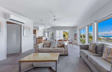 Modern hotel suite with sea view, plush sofas, kitchenette, and dining area; ideal for relaxing coastal getaways.