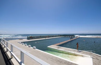 Guests enjoying outdoor oceanfront pool with clear blue skies and sea views at seaside hotel. Relaxing beach getaway.