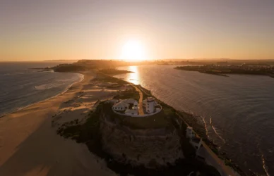 Stunning sunset view over coastal hotel, sandy beach and ocean, perfect for a tranquil getaway in nature.
