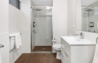 Luxurious hotel bathroom with spacious glass shower, modern fixtures, and plush towels for a relaxing stay.