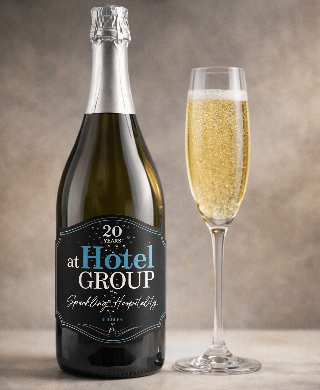 Bottle of sparkling wine with hotel-branded label beside a filled champagne flute on a neutral surface, ideal for celebrations and room service