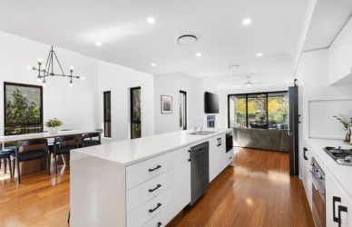 Bright open-plan kitchen and dining area with marble island, dishwasher, seating for six, wood floors and sliding doors to garden